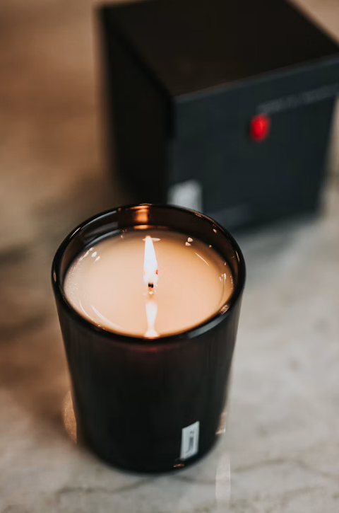 Original photograph of a lit scented candle with dark packaging